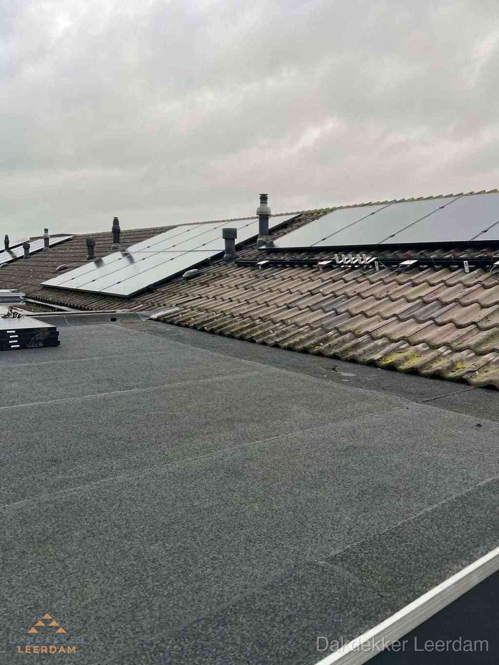 Plat dak inspectie met bitumen bedekking naast schuin pannendak in Leerdam