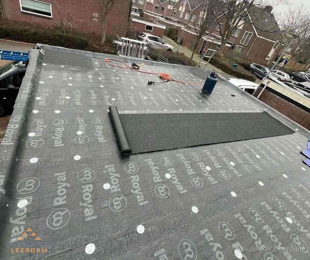 Dakdekker aan het werk met gasbrander op plat bitumen dak in Leerdam